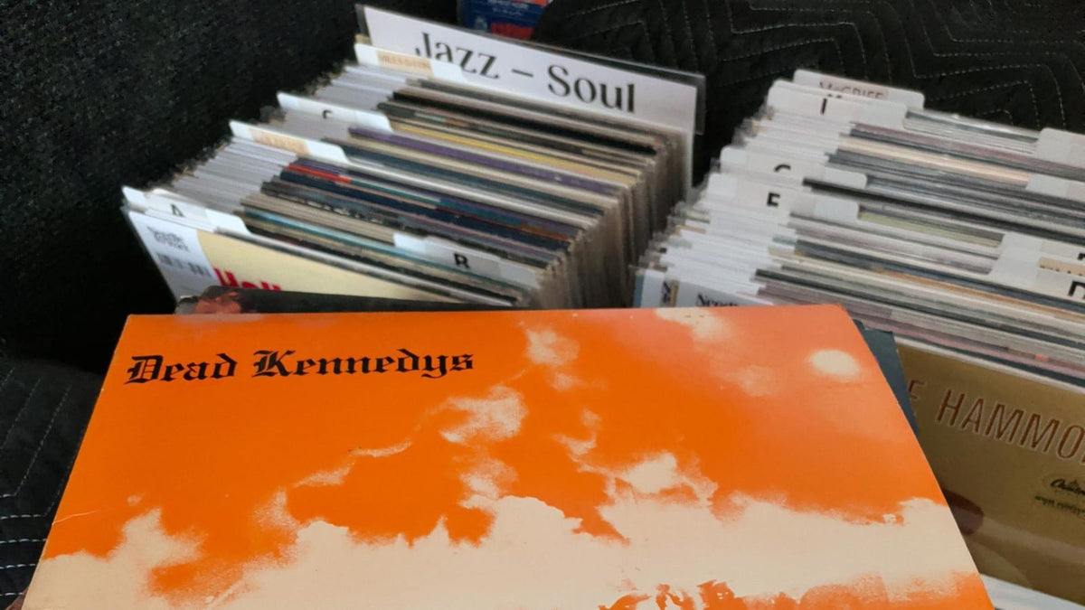 A stack of records from a collection, a Dead Kennedys LP on top, next to filed Needle to Wax crates